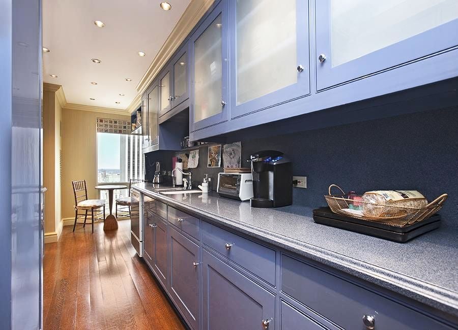 The kitchen is outfitted with hardwood floors and blue cabinets.