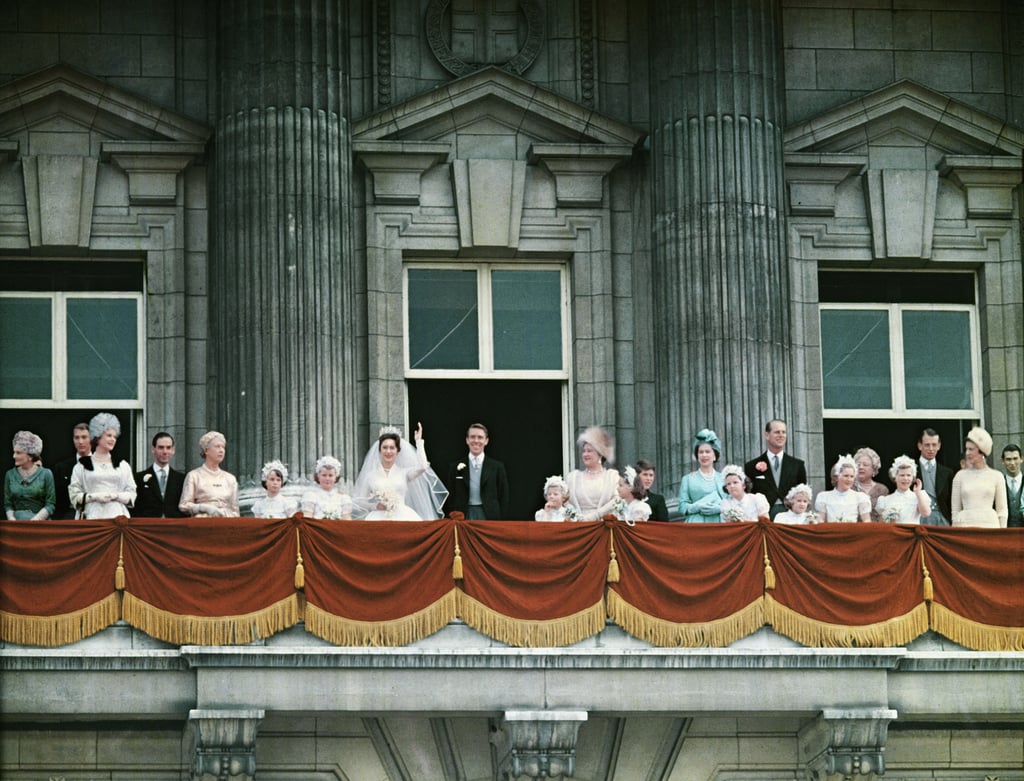 The royal family — including Queen Elizabeth II in bright blue on the right — wave from the balcony of Buckingham Palace.