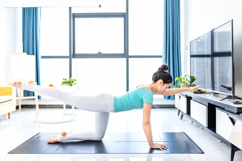 Young asian woman practicing yoga in living room