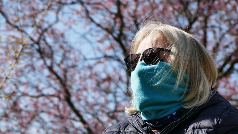 Eine ältere Frau versucht sich mit einem Schal gegen Infektion und Allergie zu schützen