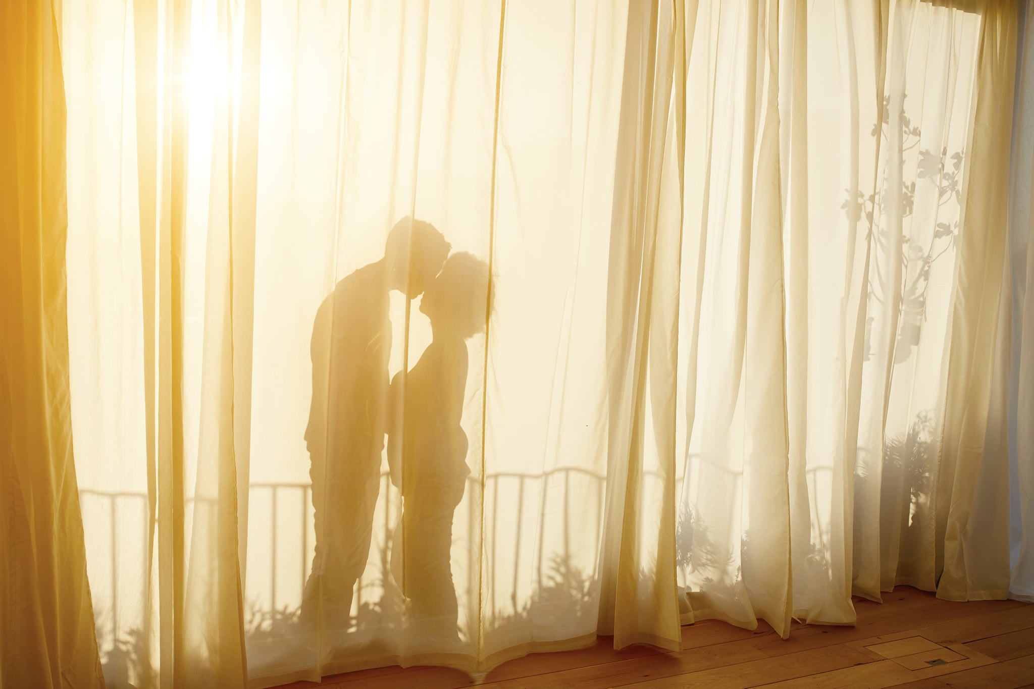 silhouette of a couple kissing behind a curtain