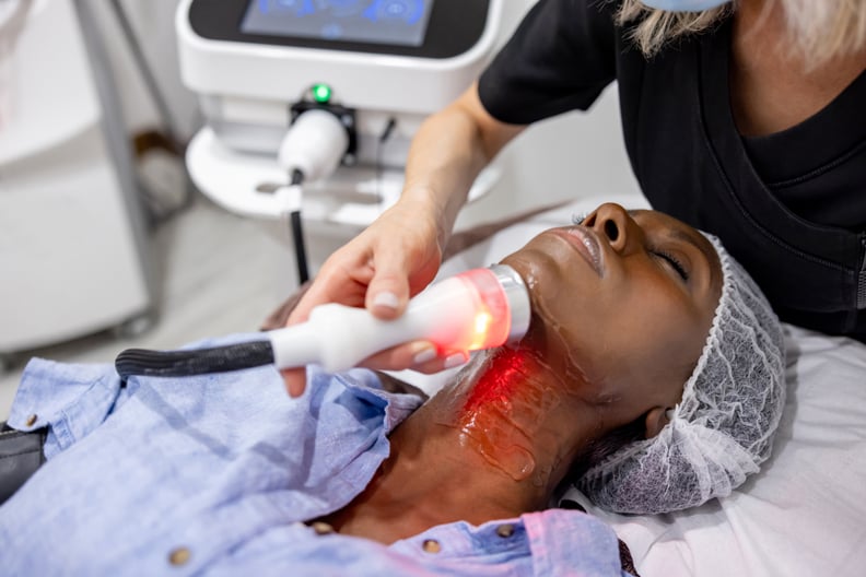 African American woman at the spa getting a rejuvenation treatment on her neck using ultrasound and light therapy