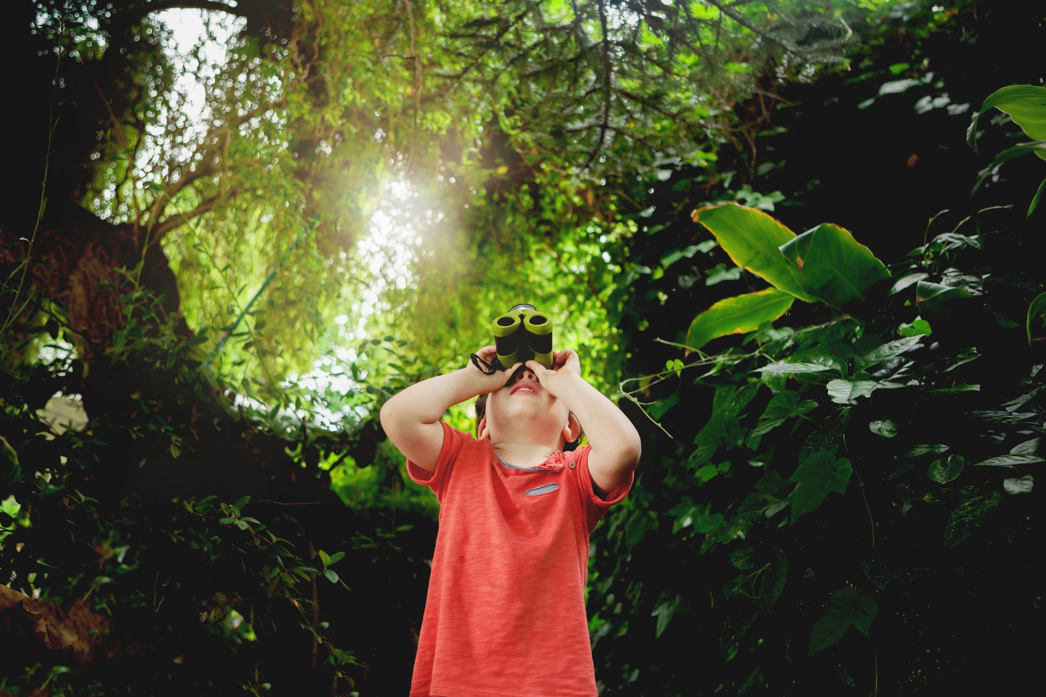 a boy looking in binoculars outdoors