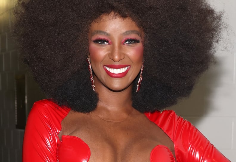 A photo of Amara La Negra smiling with a red shirt and her Afro in full force.