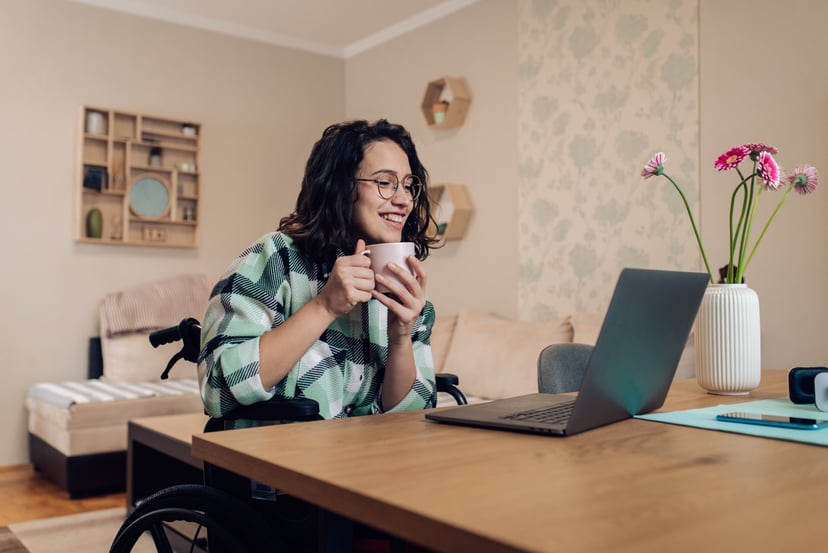 Young happy businesswoman in a wheelchair working online from home.