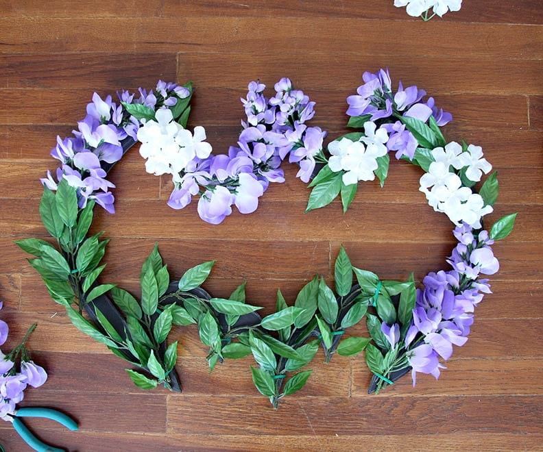It was hard to keep the Batman logo detail visible on the lower part of the wreath, so first we just wire-tied the plain leaves from the floral garland on (they’re easier to keep the shape), then we used some basic white craft glue stuff to glue little flowers onto the leaves and fill in empty spots.