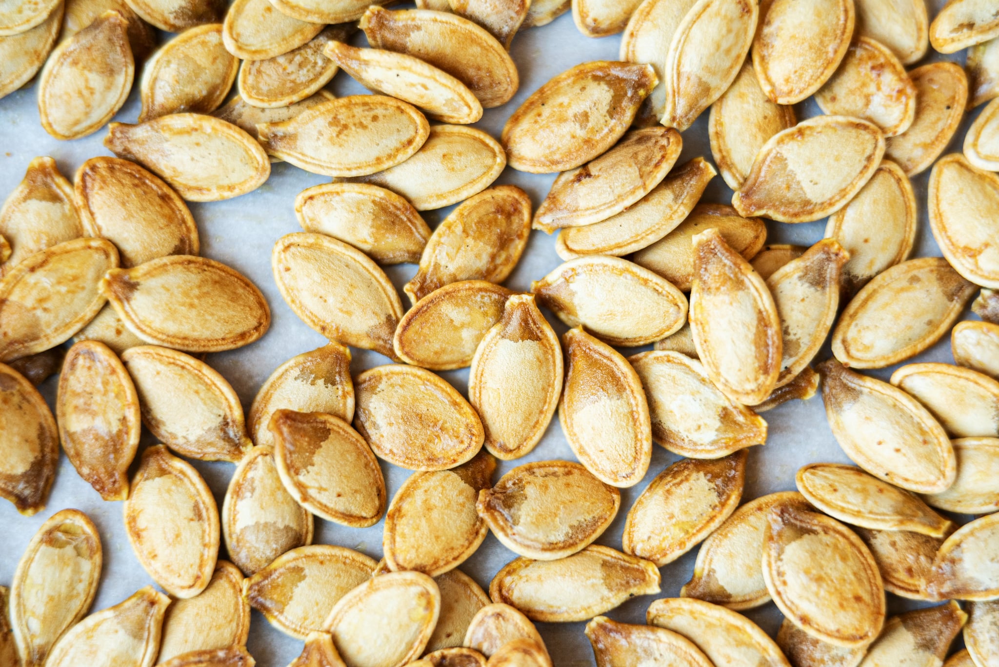 Toasted salty pumpkin seeds on parchment paper.