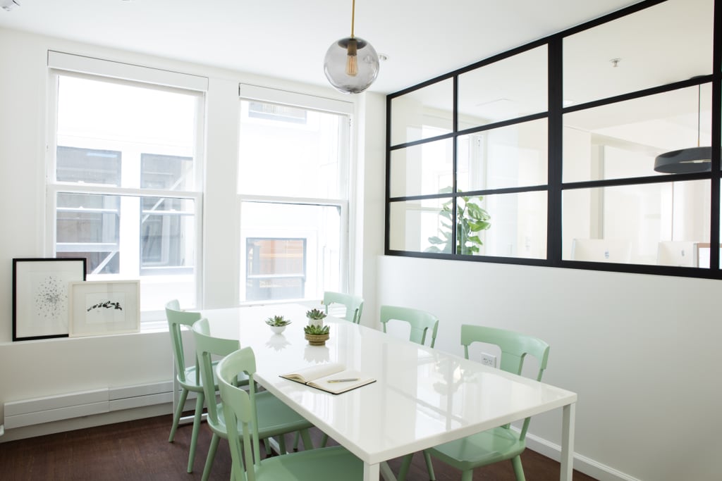 In the conference room, a sleek white and black palette is broken up with wooden chairs painted soft green. Designer Lauren opted for lighting that was less extravagant — but equally as stylish — as the lighting fixtures in the main work area.