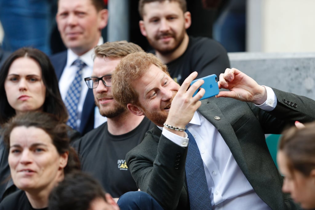 Have you ever noticed that whenever Prince Harry is doing something involved with the Invictus Games, he looks like he's having the time of his life? A few weeks after hanging out with an adorable 2-year-old at the UK team trials for the athletic competition, he brought athletes who participated in the 2014 and 2016 Invictus Games to watch the annual Army Navy rugby match in London on Saturday. Harry, who will be attending Pippa Middleton's wedding with girlfriend Meghan Markle later this month, was happy to goof off with everyone in the stands, taking selfies and making funny faces.
As Patron of the athletic competition — which is the only international sport competition for wounded, injured, and sick servicemen and women — he's been extremely involved since its inception. Last year, he kicked off the Invictus Games in Orlando, FL, with the help of Michelle Obama, and has kept in touch with the athletes ever since. Harry's Invictus Games Foundation was the official charity of this year's rugby match, so he also went onto the field to chat with some of the players from the Royal Navy and British Army, and to help sing the national anthem. Have you ever noticed that whenever Prince Harry is doing something involved with the Invictus Games, he looks like he's having the time of his life? A few weeks after hanging out with an adorable 2-year-old at the UK team trials for the athletic competition, he brought athletes who participated in the 2014 and 2016 Invictus Games to watch the annual Army Navy rugby match in London on Saturday. Harry, who will be attending Pippa Middleton's wedding with girlfriend Meghan Markle later this month, was happy to goof off with everyone in the stands, taking selfies and making funny faces.
As Patron of the athletic competition — which is the only international sport competition for wounded, injured, and sick servicemen and women — he's been extremely involved since its inception. Last year, he kicked off the Invictus Games in Orlando, FL, with the help of Michelle Obama, and has kept in touch with the athletes ever since. Harry's Invictus Games Foundation was the official charity of this year's rugby match, so he also went onto the field to chat with some of the players from the Royal Navy and British Army, and to help sing the national anthem.