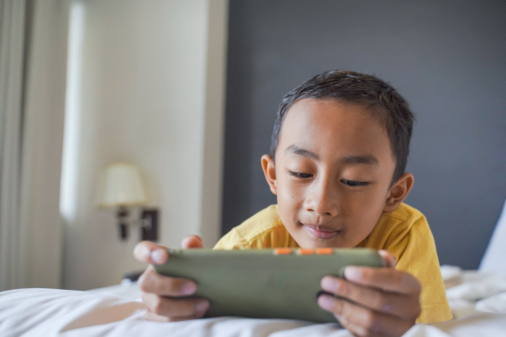 Asian young boy using smartphone in the bedroom