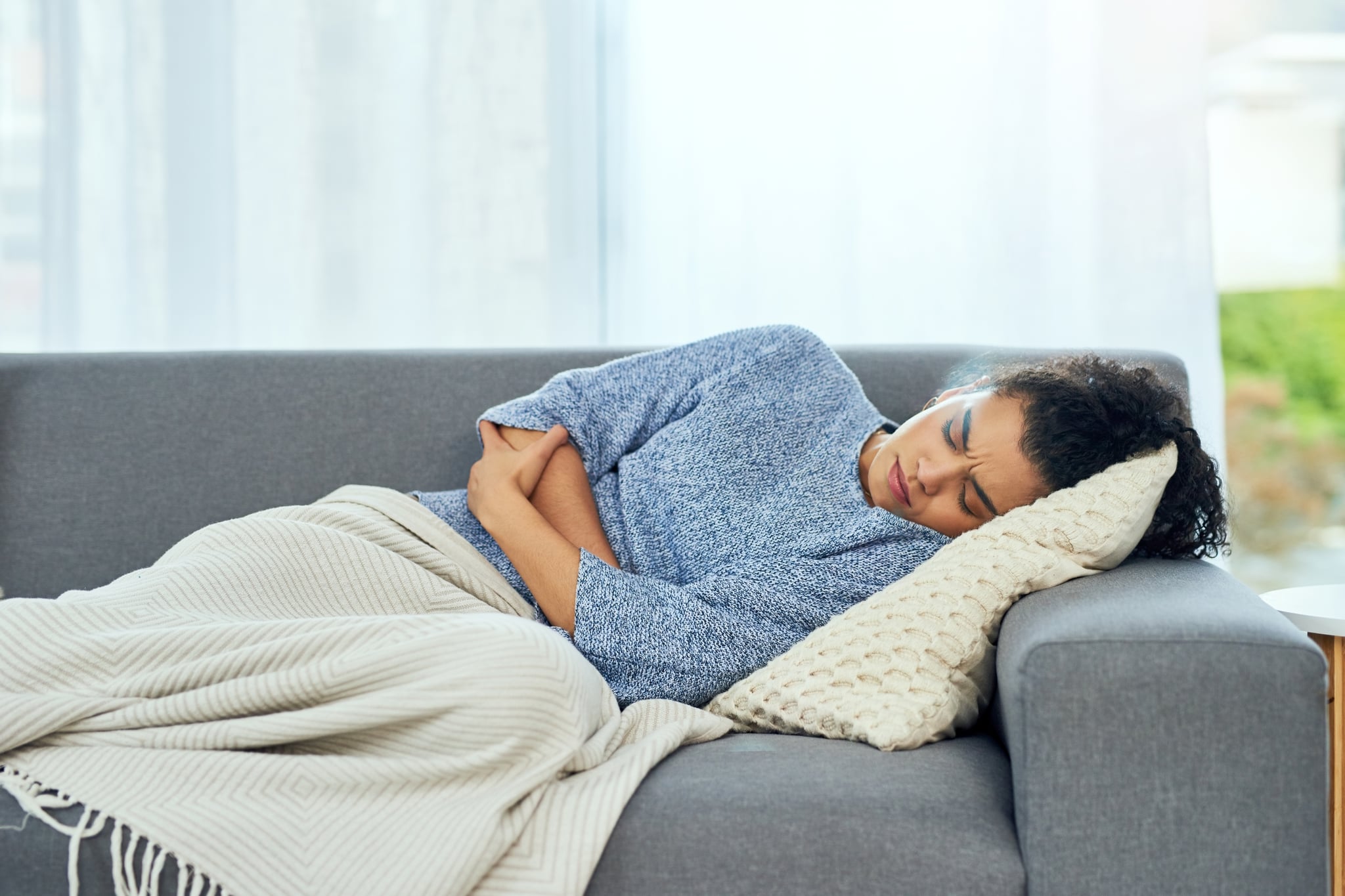 Shot of a young woman experiencing stomach pain on the sofa at home