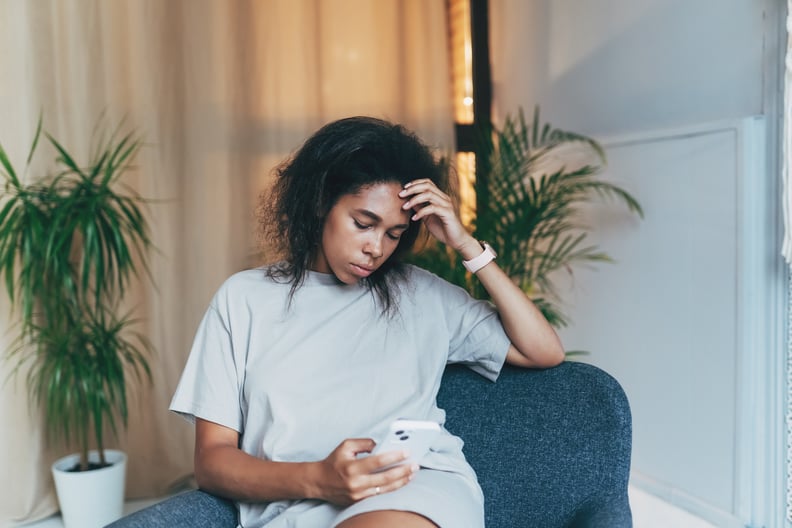 Woman sitting and doomscrolling on her phone.