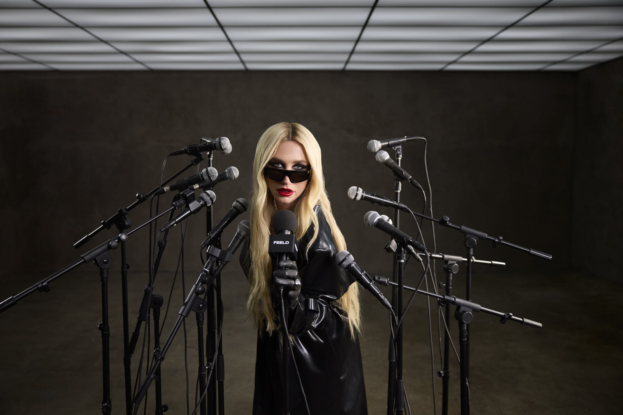 Kesha wearing leather talking into microphones for her partnership with Feeld.