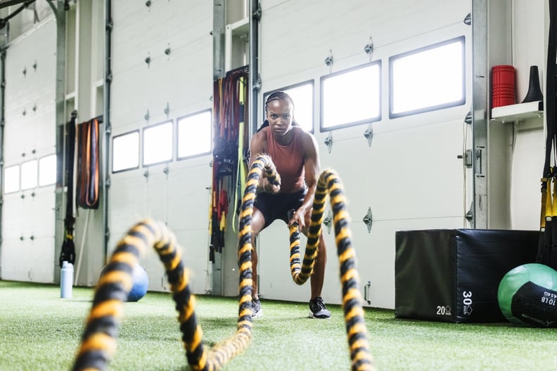 Woman swinging battle ropes at the gym.