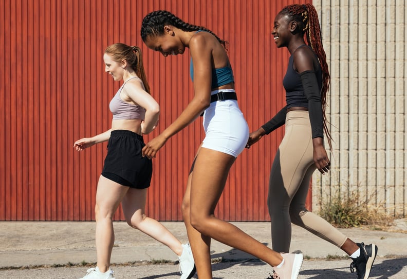 Group of women walking together on concrete sidewalk.