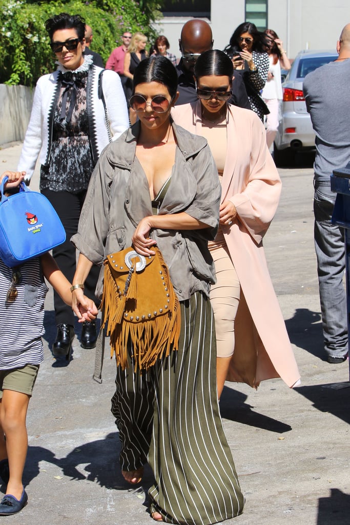 Kourtney chose wide leg pinstripe pants that were part of her crop top set. She covered up with a gray parka jacket.