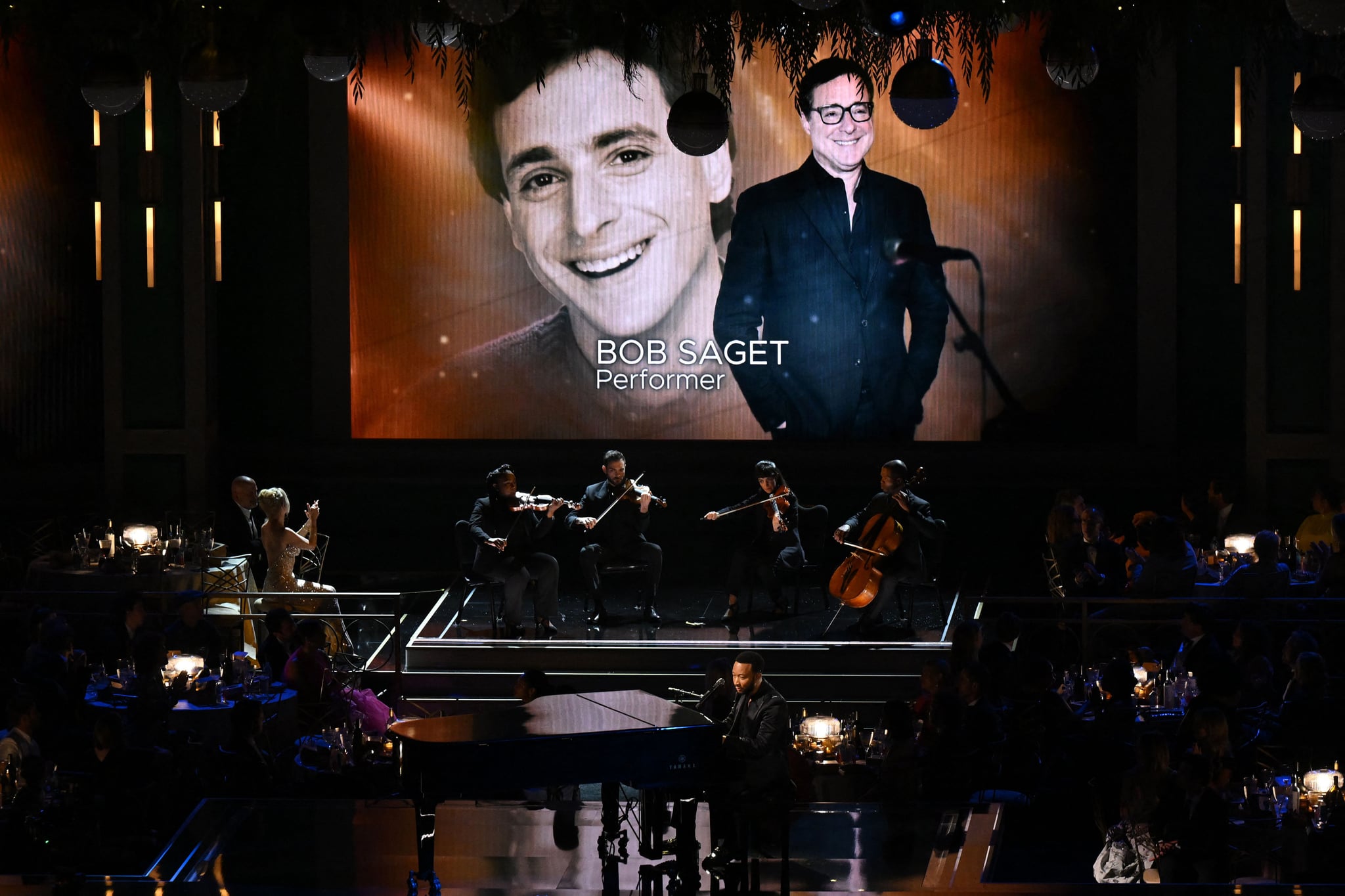 Late US actor Bob Saget is seen onscreen during an In Memoriam segment performed by US singer-songwriter John Legend onstage during the 74th Emmy Awards at the Microsoft Theater in Los Angeles, California, on September 12, 2022. (Photo by Patrick T. FALLON / AFP) (Photo by PATRICK T. FALLON/AFP via Getty Images)