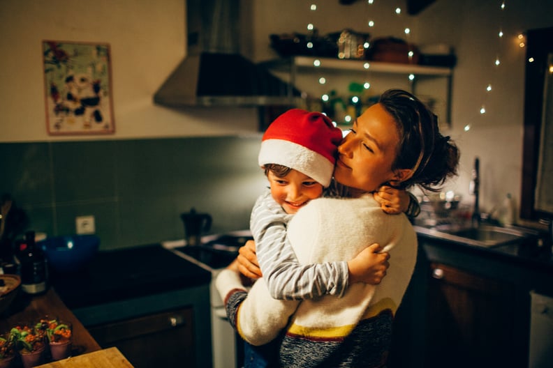mom hugging her son wearing a Santa hat in the kitchen