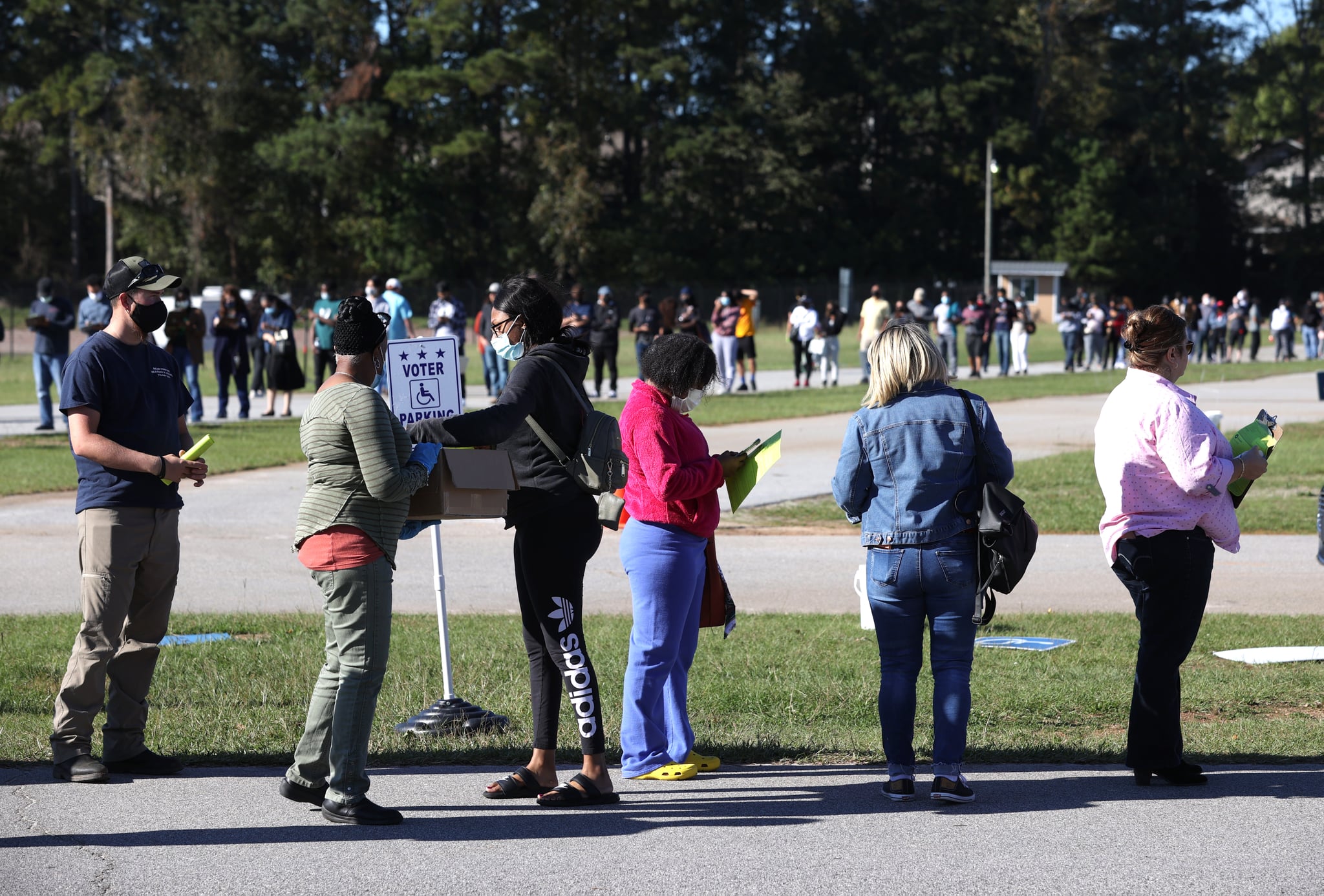 LAWRENCEVILLE, GEORGIA - OCTOBER 30: A poll worker hands out pens and clipboards to fill out registration cards as people stand in line to vote at the Gwinnett County Fairgrounds on October 30, 2020 in Lawrenceville, Georgia. Hundreds of people lined up for about an hour to cast their ballot on the final day of early voting in Georgia. (Photo by Justin Sullivan/Getty Images)