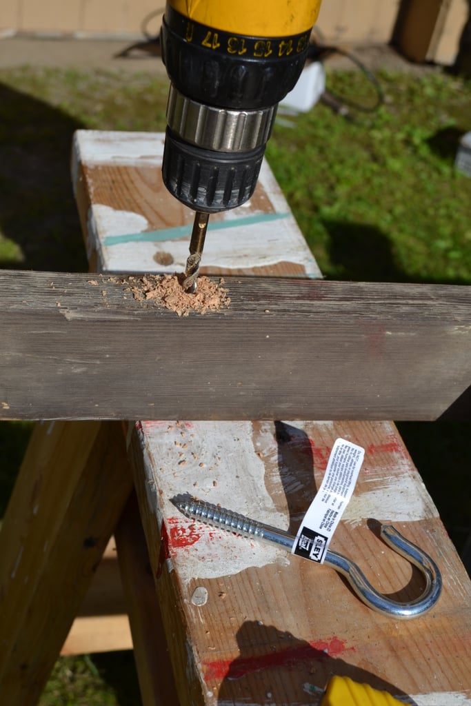 Mark where your hooks will be to hang your ladder based on where your studs in the ceiling are (make sure they are placed in a stud or that there is bracing in the ceiling — sheetrock alone won’t hold it up). Then predrill holes for your large hook — make sure the drill bit is smaller than the hook; you want it to be tough to get the hook in because you don’t want it sliding out.