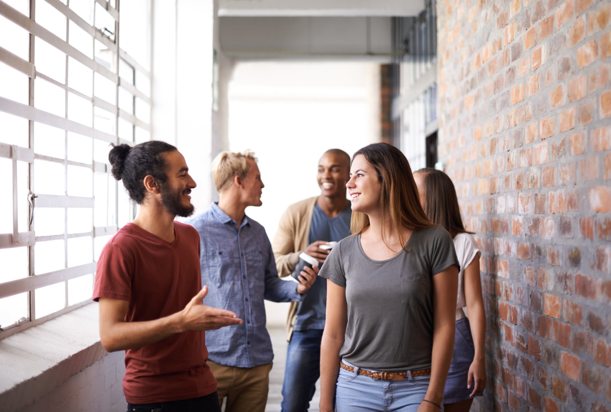 Shot of a diverse group of university friends talking in a hallway