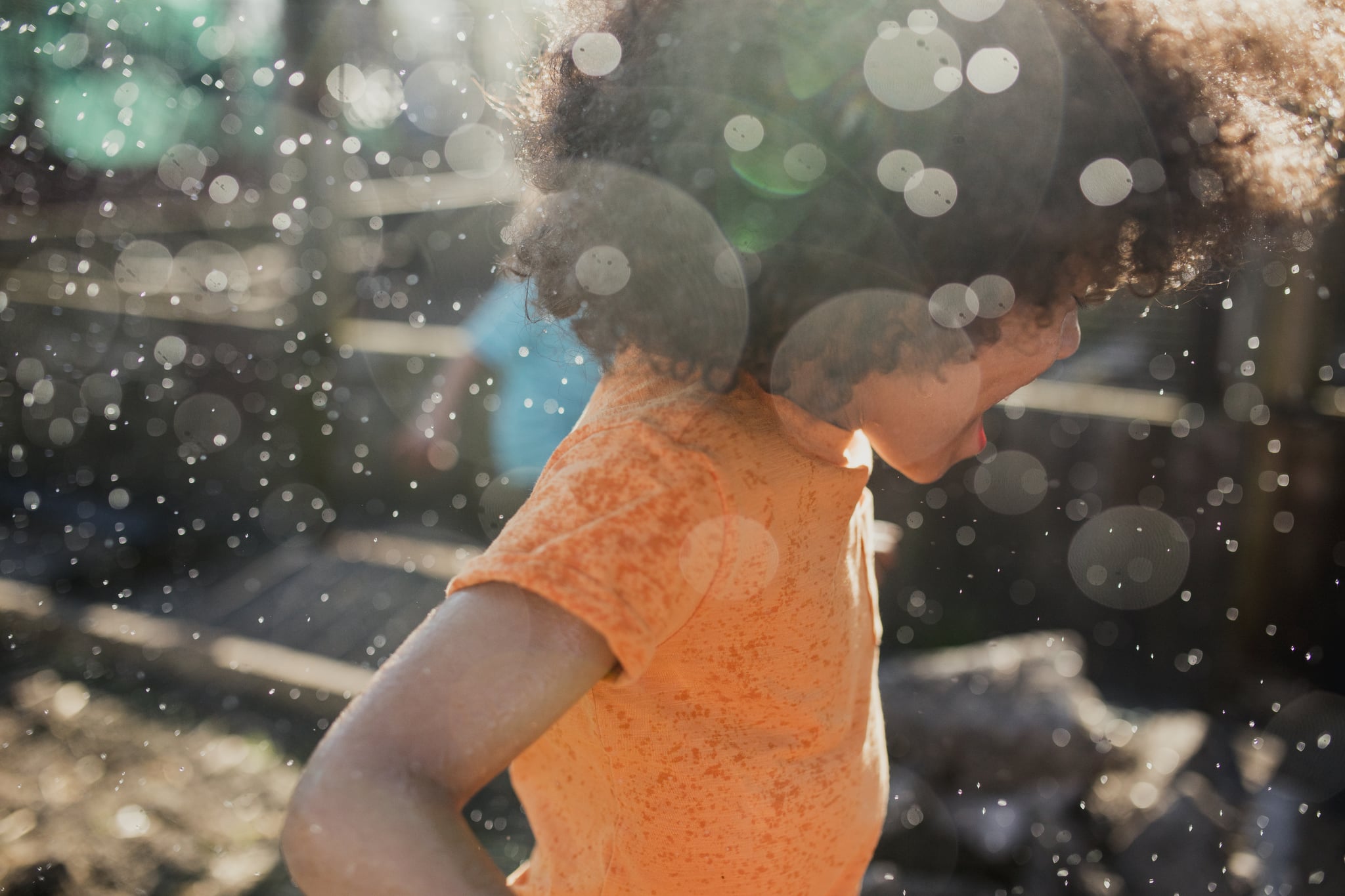 Little boy is playing in the sprinkler water while at the allotment.