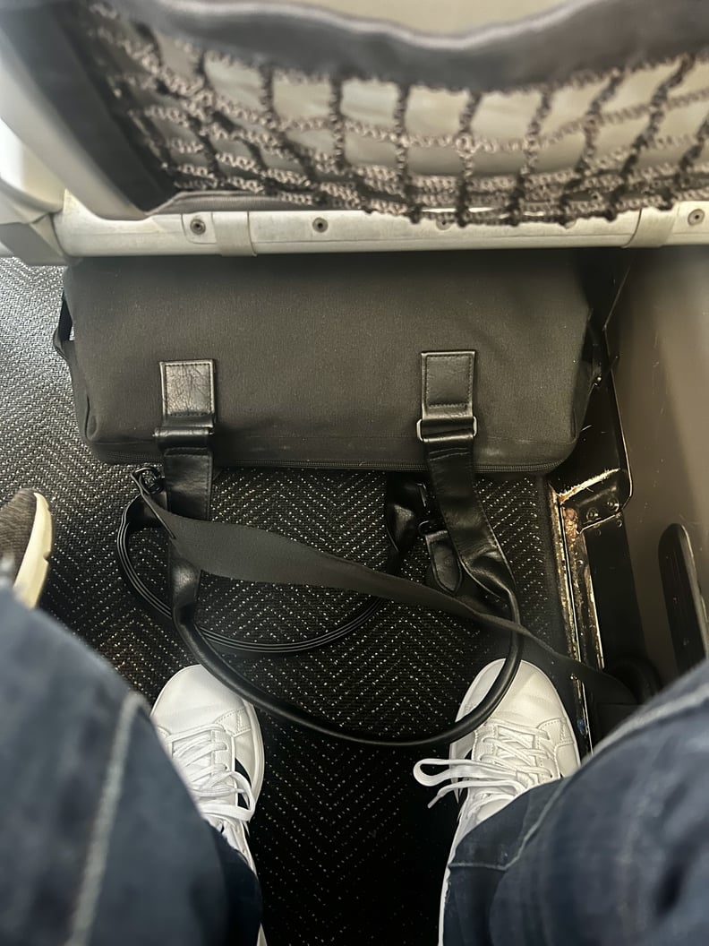 The Béis Mini Weekender underneath the seat in an aircraft.