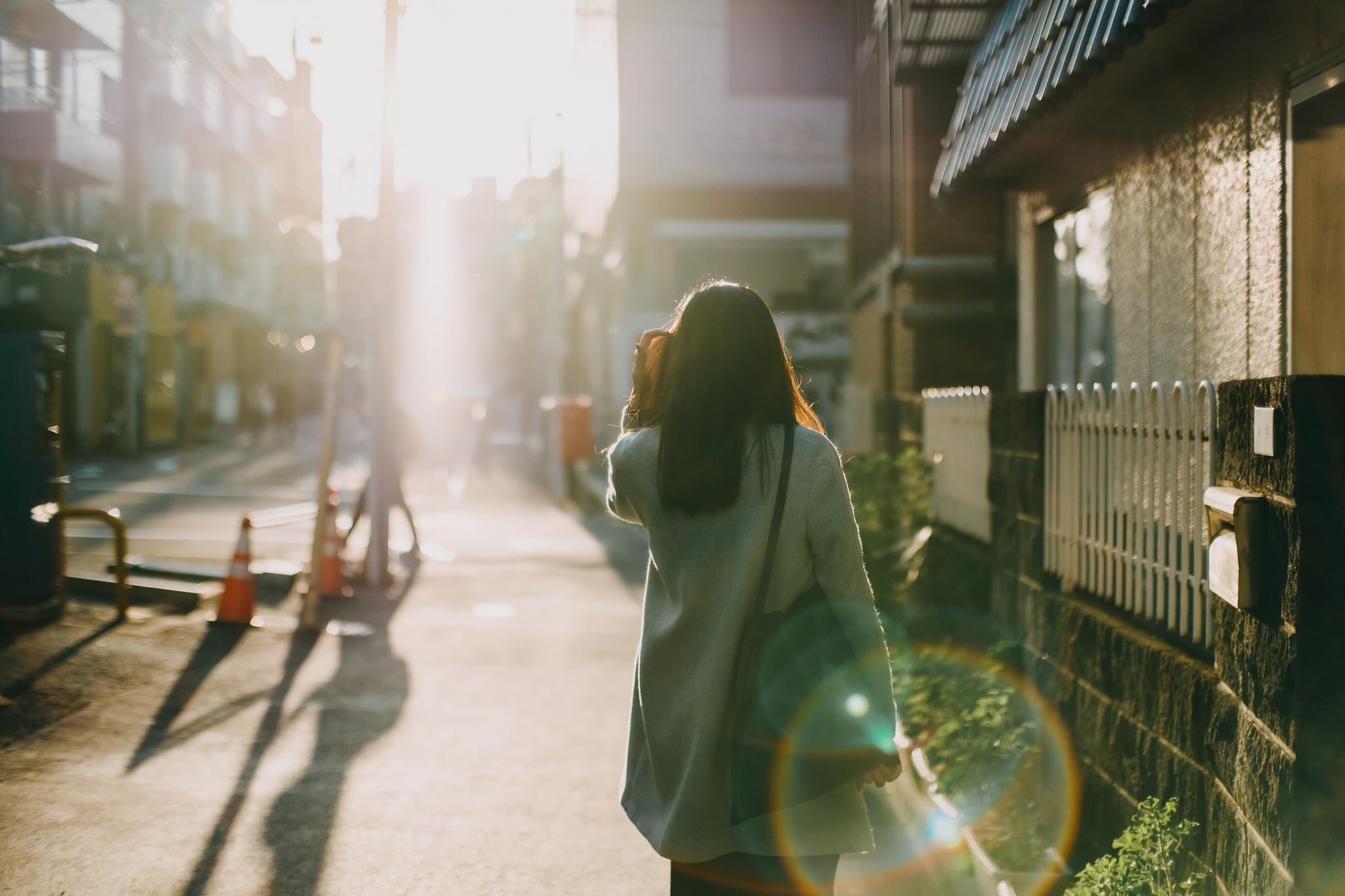 Rear view of woman leaving home to work in the early morning against warm sunlight