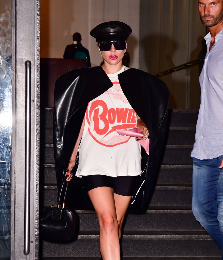 Wearing a graphic tee paired with a leather black cape and Moschino sunglasses.