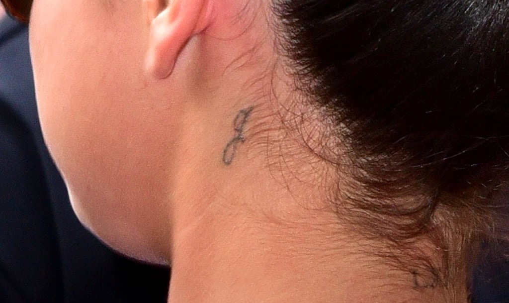 Don't freak out! It's not a "J" for Justin. The "G" behind Selena's ear is there to represent Gracie, her little sister.