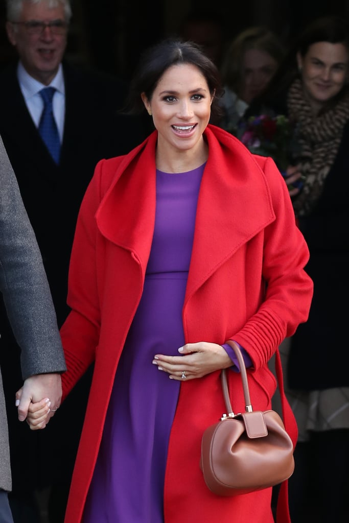 While visiting Birkenhead in 2019, a pregnant Markle wowed us all in a  red Sentaler coat over Aritzia Babaton Maxwell dress, accompanied by a tan Gabriela Hearst bag.