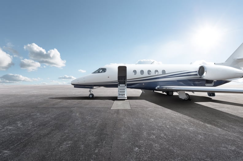 Private jet on airport runway against blue sky.