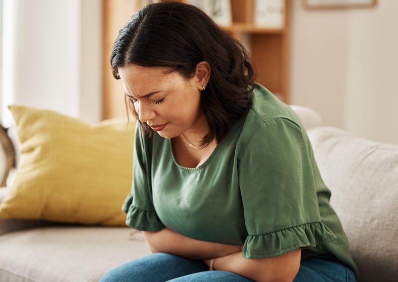 Woman on the couch dealing with nausea.