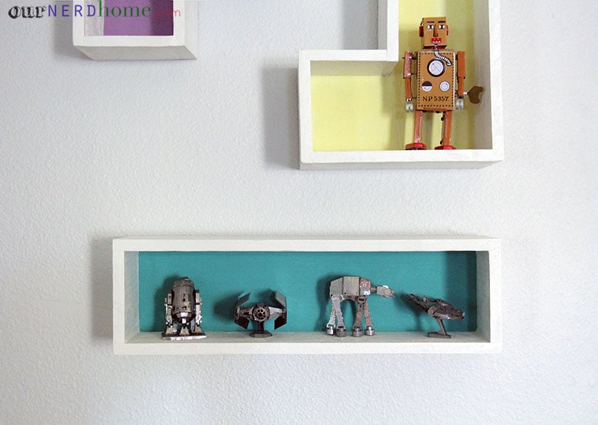 We're debating if we should leave the shelves bare or use them as display shelves. Here they are with stuff. Those are the Star Wars Metal Model Kits from ThinkGeek on the bottom shelf. Which we love (plus they were fun to put together!). The vintage-y robot on the yellow shelf is this awesome guy. And yes, he winds up and walks.