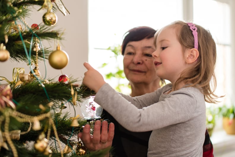 Girl child tying decorative objects on christmas tree