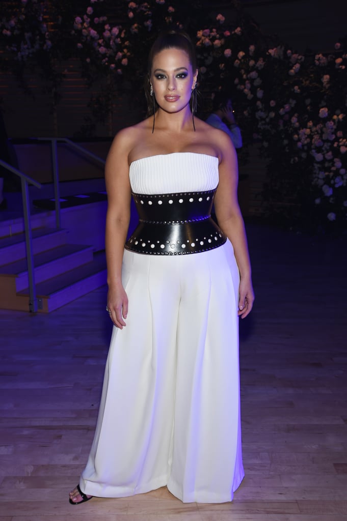 Sitting front row at Brandon Maxwell wearing a white strapless jumpsuit with a black leather corset belt.