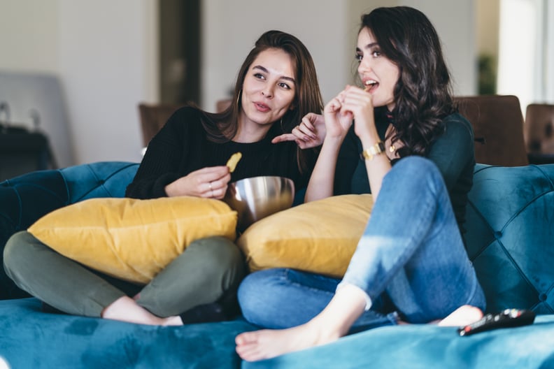 Two young women friends are watching TV together.