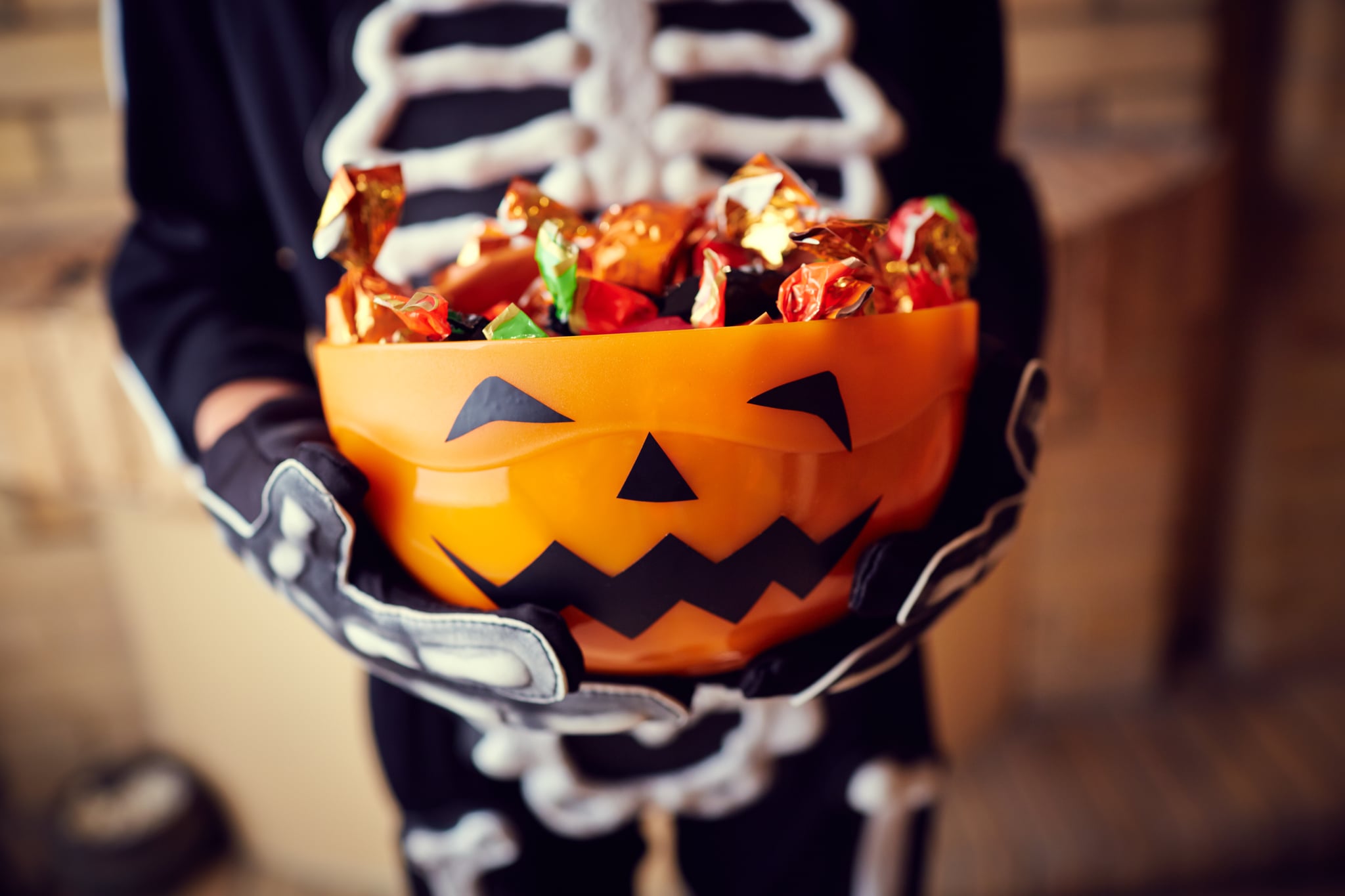 Boy in skeleton costume holding bowl full of candies