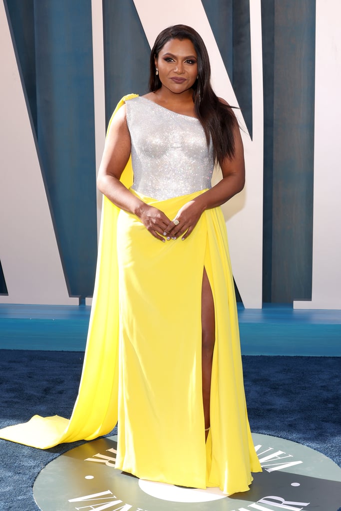 Kaling wore a sculptural, one-shoulder dress with a silver metallic bodice, yellow skirt, and single-shoulder cape at the 2022 Vanity Fair Oscars party. She played up her leg slit with silver platforms and finished the outfit with Martin Katz jewels.