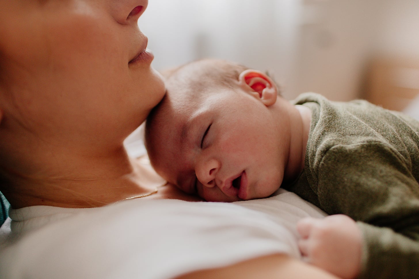 Woman laying down holding baby on her chest.