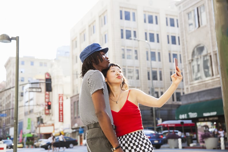 A young couple taking a selfie on a city street with a mobile device